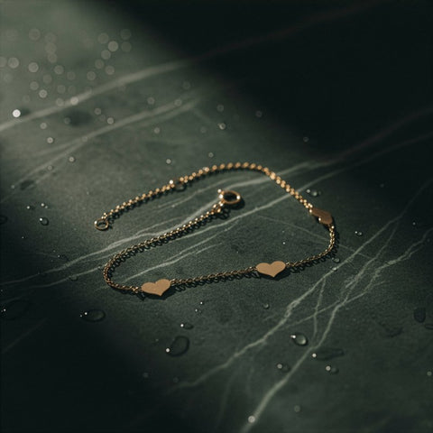 Gold bracelet with heart charms on a dark surface