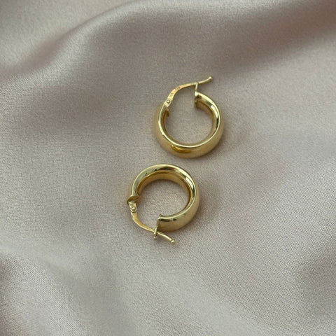 Gold hoop earrings on a beige fabric background